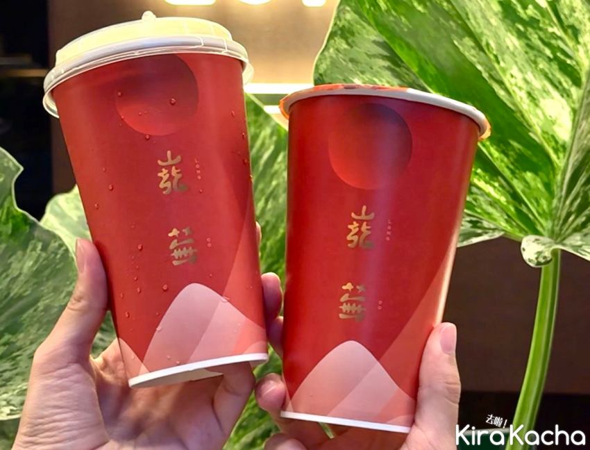 「巃蕪」台茶系列飲品登場，紅金杯身映襯綠植背景，展現自然與茶文化的融合。