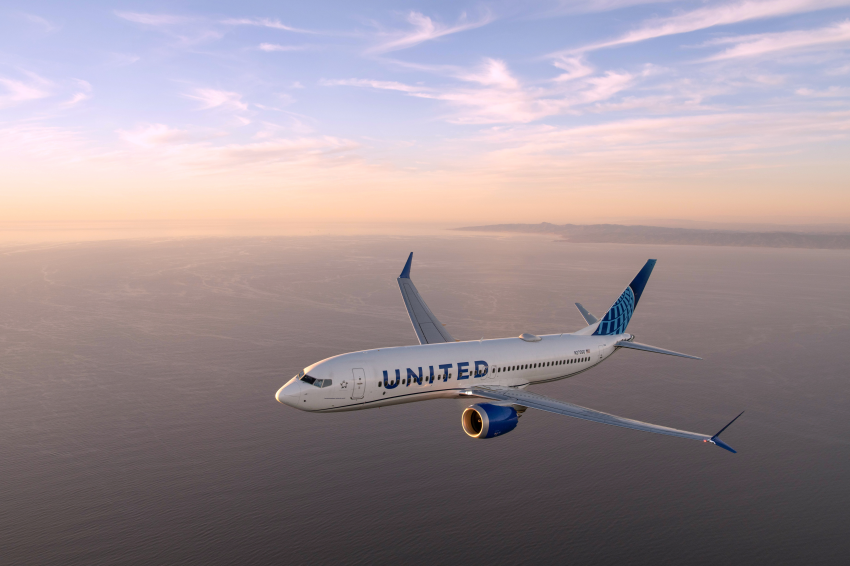 United客機飛行於夕陽映照的天空。